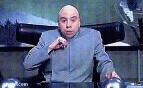 A Bald Man Is Sitting At A Desk With His Hand On His Chin GIF