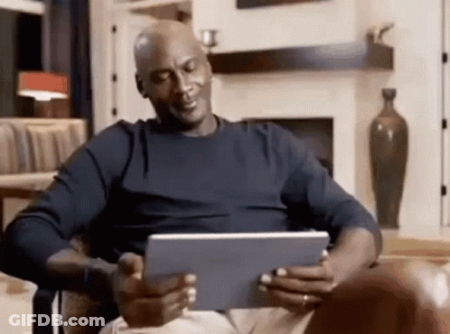 A Bald Man Is Sitting In A Chair Looking At A Tablet Computer . GIF