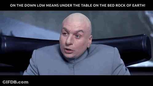 A Bald Man Is Sitting In A Chair With The Words On The Down Low Means Under The Table On The Bed Rock Of Earth Below Him GIF