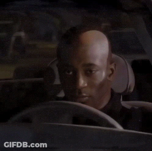 A Bald Man Is Sitting In The Driver 'S Seat Of A Car . GIF