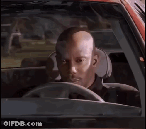 A Bald Man Is Sitting In The Driver 'S Seat Of A Car Looking At The Camera . GIF