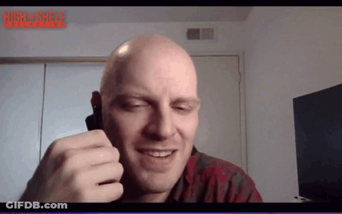 A Bald Man Is Smiling In Front Of A Screen That Says High Shelf Interactive GIF