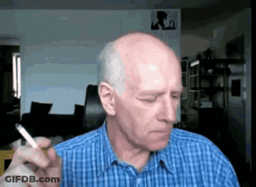 A Bald Man Is Smoking A Cigarette In A Blue Plaid Shirt GIF
