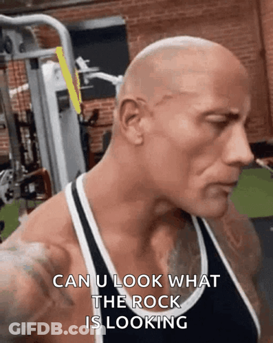 A Bald Man Is Standing In A Gym With The Words `` Can U Look What The Rock Is Looking '' On His Face . GIF