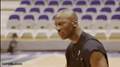 A Bald Man Is Standing On A Basketball Court . GIF