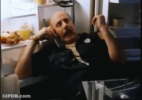 A Bald Man Is Talking On A Cell Phone In A Refrigerator . GIF