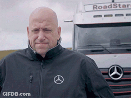 A Bald Man Stands In Front Of A Mercedes Truck GIF
