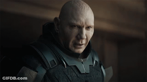A Bald Man Wearing A Black Armored Suit Looks At The Camera GIF