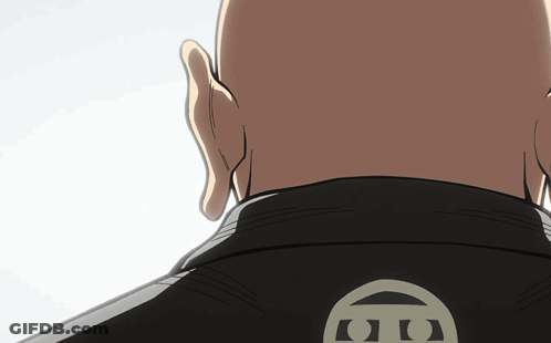 A Bald Man Wearing A Black Jacket With The Letter G On The Back Of It GIF