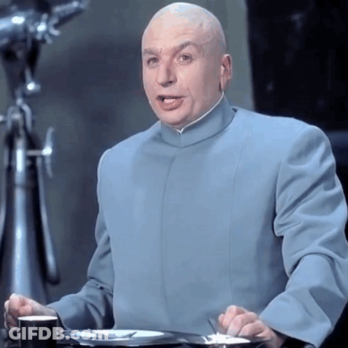 A Bald Man Wearing A Blue Suit Is Sitting At A Table GIF