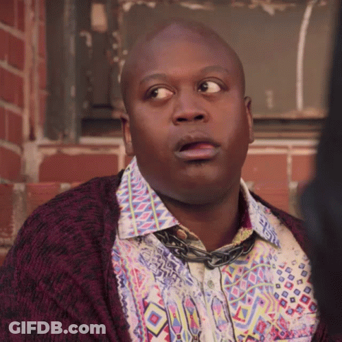 A Bald Man Wearing A Colorful Shirt And A Purple Cardigan Looks Surprised GIF