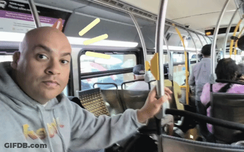 A Bald Man Wearing A Grey Hoodie With The Word Houston On It Rides A Bus GIF