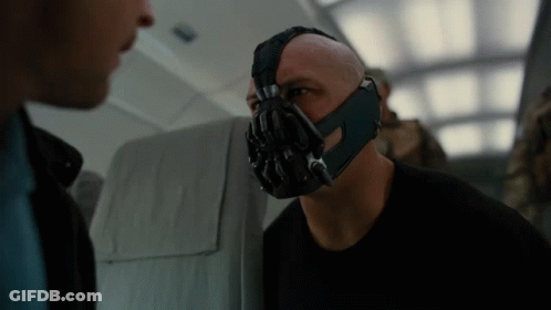 A Bald Man Wearing A Mask Talks To Another Man GIF