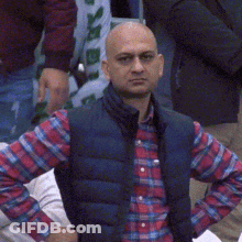 A Bald Man Wearing A Plaid Shirt And A Vest GIF