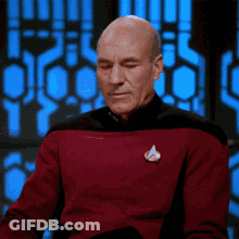 A Bald Man Wearing A Red Sweater With A Star Trek Logo On His Chest GIF