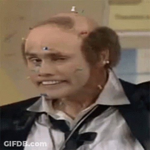 A Bald Man Wearing A Suit And Tie Has A Bunch Of Wires Stuck To His Head . GIF