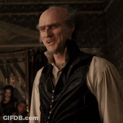 A Bald Man Wearing A Vest And A White Shirt Is Smiling GIF