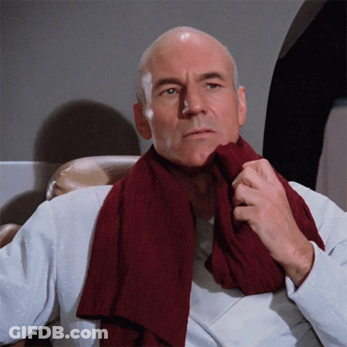A Bald Man Wearing A White Shirt And A Maroon Scarf Around His Neck GIF