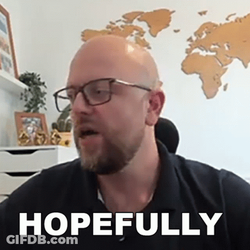 A Bald Man Wearing Glasses And A Black Shirt Says Hopefully In Front Of A Map Of The World . GIF