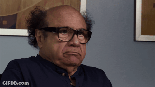 A Bald Man Wearing Glasses And A Blue Shirt Is Making A Funny Face GIF