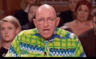 A Bald Man Wearing Glasses And A Colorful Shirt Is Standing In Front Of A Crowd . GIF