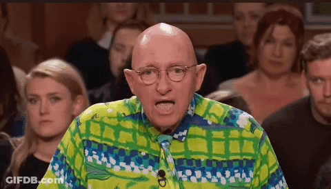 A Bald Man Wearing Glasses And A Colorful Shirt Stands In Front Of A Crowd . GIF