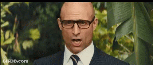 A Bald Man Wearing Glasses And A Suit And Tie Is Making A Funny Face . GIF