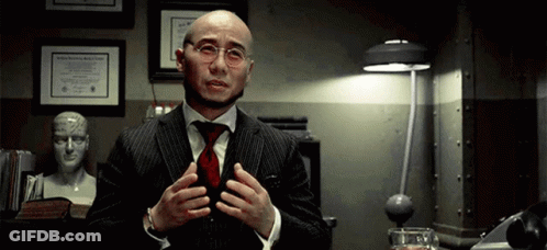 A Bald Man Wearing Glasses And A Suit Is Talking GIF