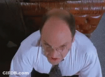 A Bald Man Wearing Glasses And A White Shirt And Tie Is Looking Up At The Camera . GIF