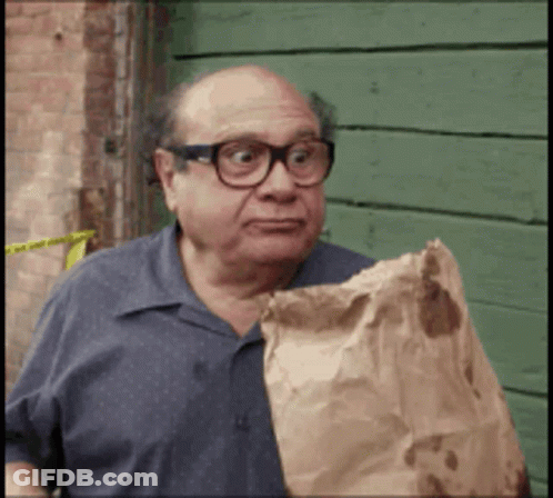 A Bald Man Wearing Glasses Is Holding A Brown Bag GIF