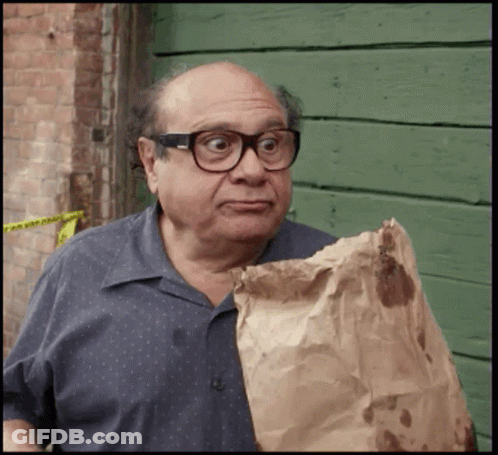 A Bald Man Wearing Glasses Is Holding A Brown Bag GIF