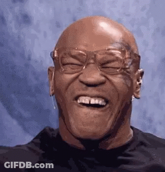 A Bald Man Wearing Glasses Is Laughing With His Eyes Closed And His Mouth Open . GIF