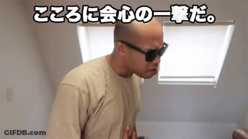 A Bald Man Wearing Sunglasses And A Tan Shirt Is Standing In Front Of A Window With Chinese Writing Behind Him GIF