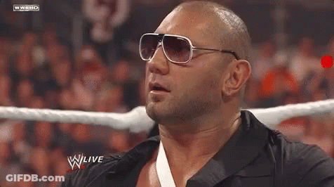 A Bald Man Wearing Sunglasses Is In A Wrestling Ring . GIF