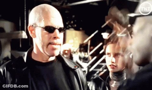 A Bald Man Wearing Sunglasses Is Standing Next To A Woman GIF