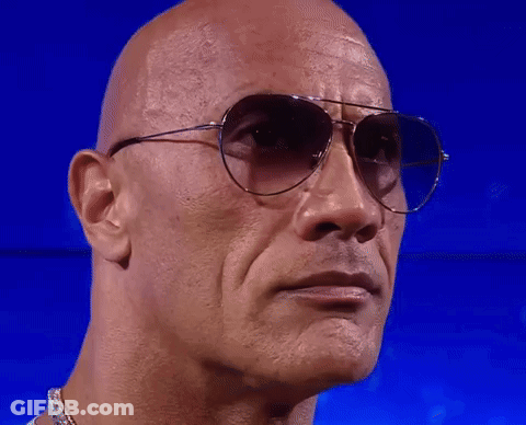 A Bald Man Wearing Sunglasses Looks At The Camera GIF