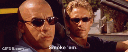 A Bald Man Wearing Sunglasses Says " Smoke 'Em " While Another Man Looks On GIF