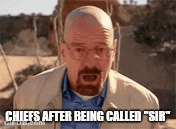A Bald Man With A Beard And Glasses Is Standing In The Desert And Talking . GIF