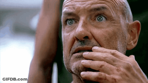 A Bald Man With A Beard Is Covering His Mouth With His Hands GIF