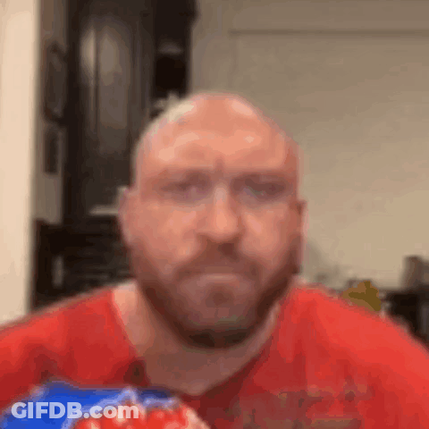 A Bald Man With A Beard Is Eating A Bag Of Doritos . GIF