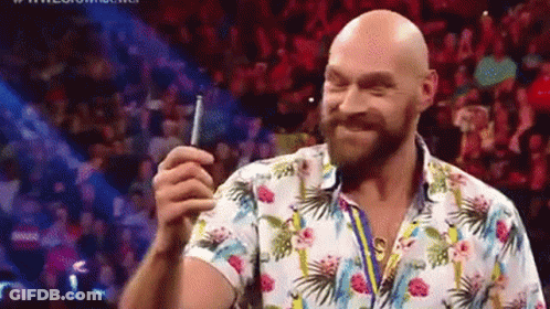 A Bald Man With A Beard Is Holding A Cell Phone In Front Of A Crowd Of People . GIF