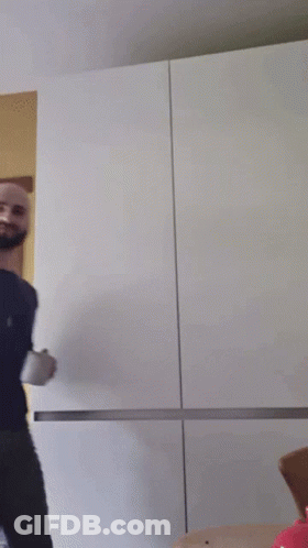 A Bald Man With A Beard Is Holding A Cup GIF
