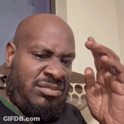 A Bald Man With A Beard Is Holding Something In His Hand And Making A Face GIF