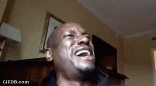 A Bald Man With A Beard Is Laughing In A Room GIF