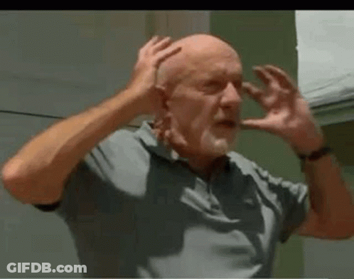 A Bald Man With A Beard Is Making A Funny Face With His Hands On His Head . GIF