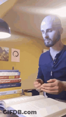 A Bald Man With A Beard Is Reading A Book GIF