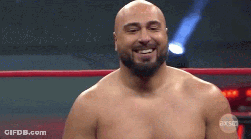 A Bald Man With A Beard Is Standing In A Wrestling Ring Smiling . GIF