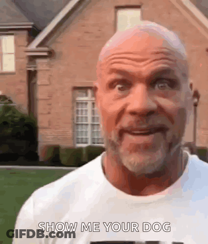 A Bald Man With A Beard Is Standing In Front Of A Brick House And Saying Show Me Your Dog . GIF