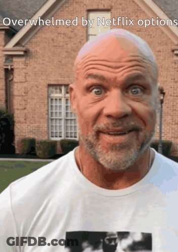A Bald Man With A Beard Is Standing In Front Of A Brick House With The Words Overwhelmed By Netflix Options Below Him GIF