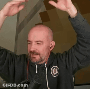 A Bald Man With A Beard Is Standing In Front Of A Microphone . GIF